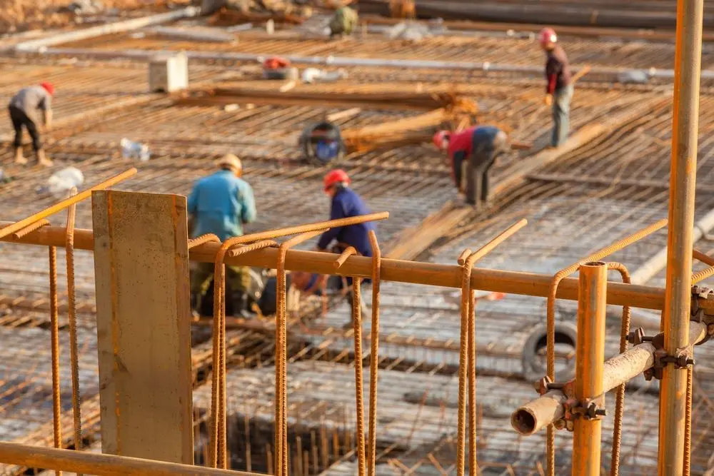 Construction workers laying down foundation at a job site.