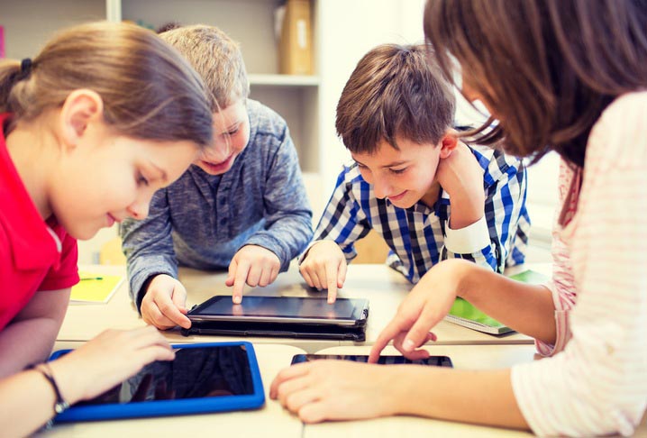 a group of students in a mobile classroom are sitting around a table while working on tablets with the teacher