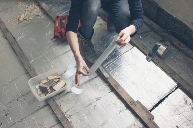 Woman using heat tape to insulate the floor. 