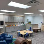 interior of modular educational toddler classroom with cabinets tables and chairs