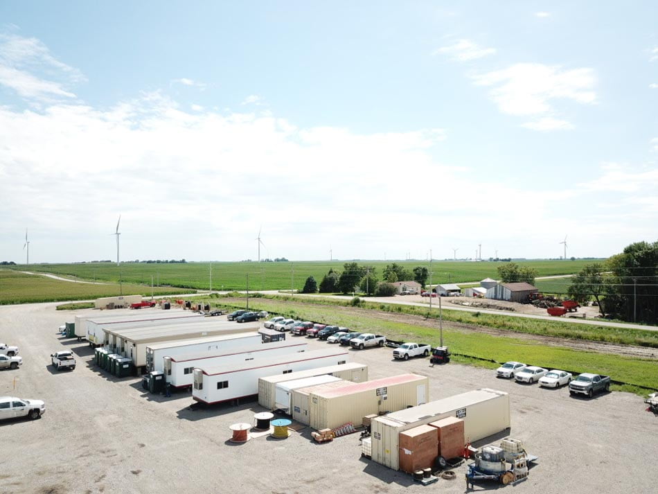 Row of modular office trailers, with windmills in fields in the background.
