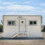 Front view of an 8x24 mobile office with steps leading up to a single door.
